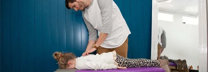 Pediatric Chiropractor Max Carlin Adjusting Young Patient With Back Pain