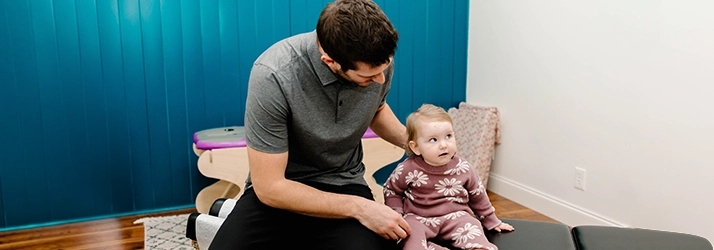 Pediatric Chiropractor Max Carlin Sitting With Infant Patient