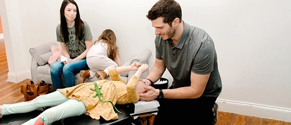 Pediatric Chiropractor Max Carlin With Young Patient And Her Family